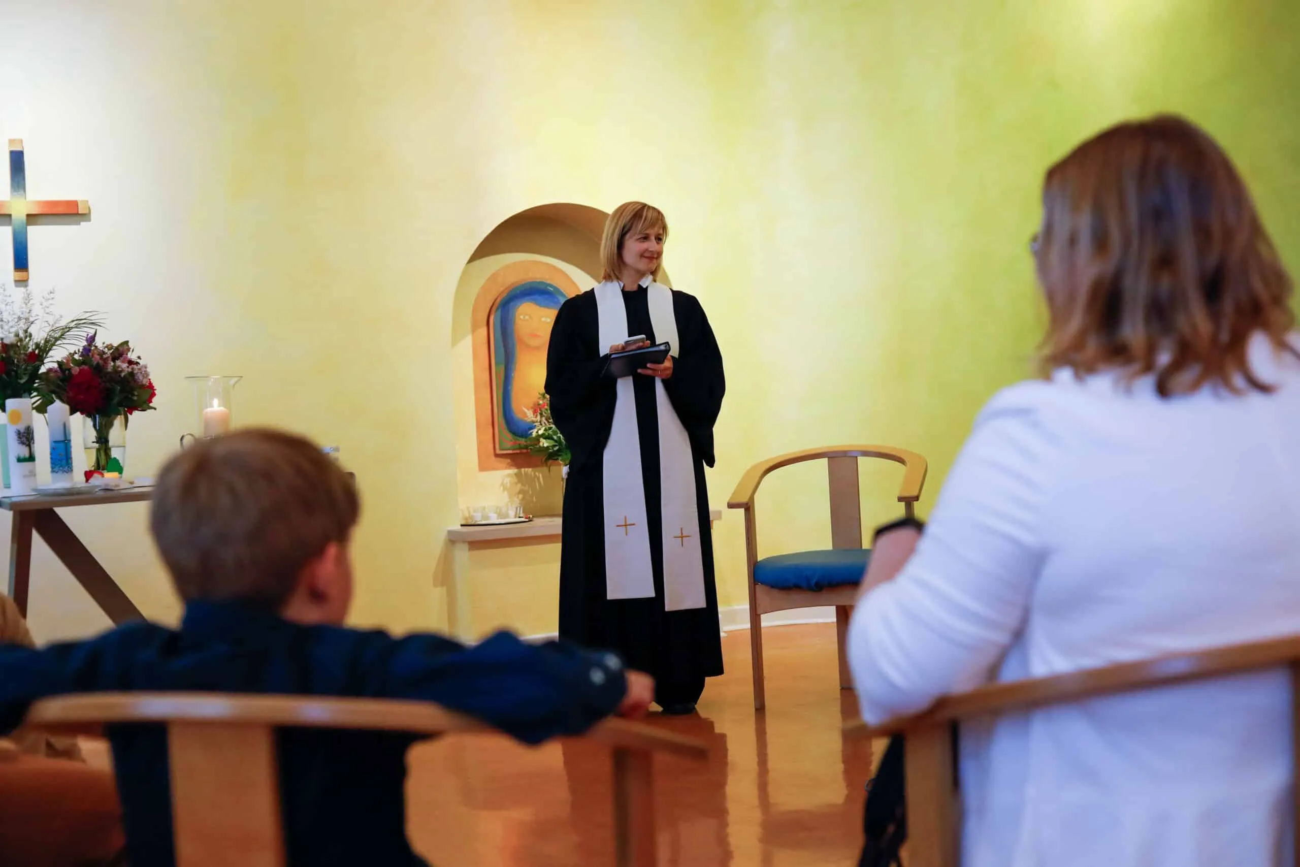 Eine Pfarrerin im Talar spricht in der Krankenhauskapelle zur versammelten Familie.