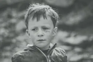 Schwarz-Weiß-Porträt eines Jungen mit ernstem Blick im Freien.