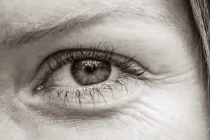 Nahaufnahme eines Auges in Sepiatönen mit feinen Wimpern und zarten Fältchen.